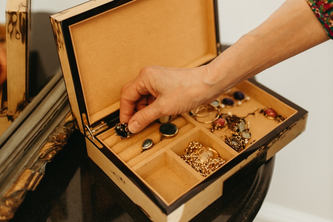An older woman reaches for a ring in her jewelry box.