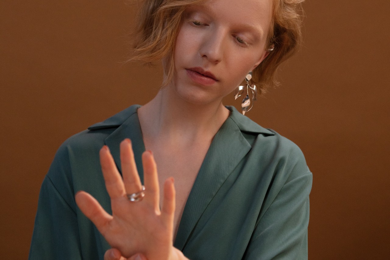 Woman admiring a platinum fashion ring while wearing a bold statement platinum earrings as well
