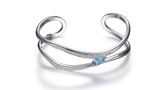A sculptural silver cuff bracelets with a light blue gemstone and diamond accents