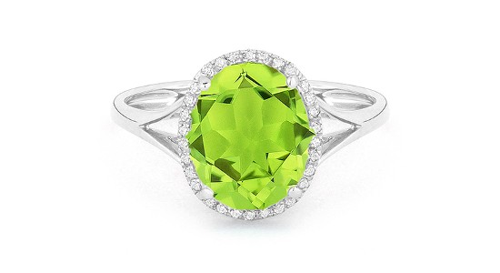 A silver ring featuring an oval cut peridot with a diamond halo