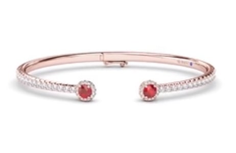 A rose gold cuff bracelet features ruby gemstone accents