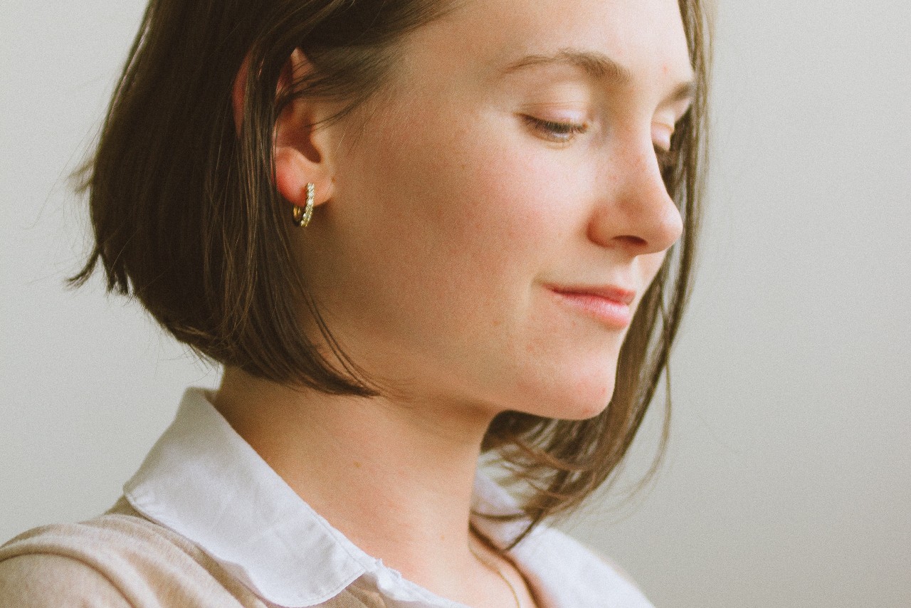 A woman looking away from the camera and wearing a simple diamond huggie