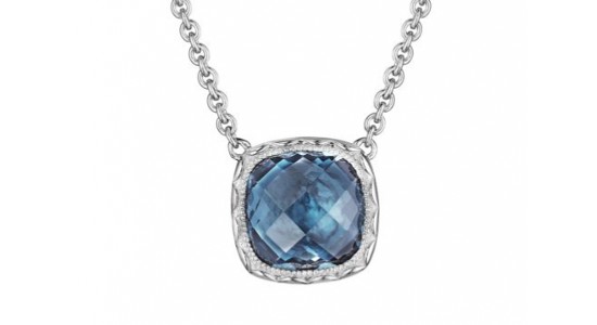 a white gold pendant necklace featuring a deep blue topaz