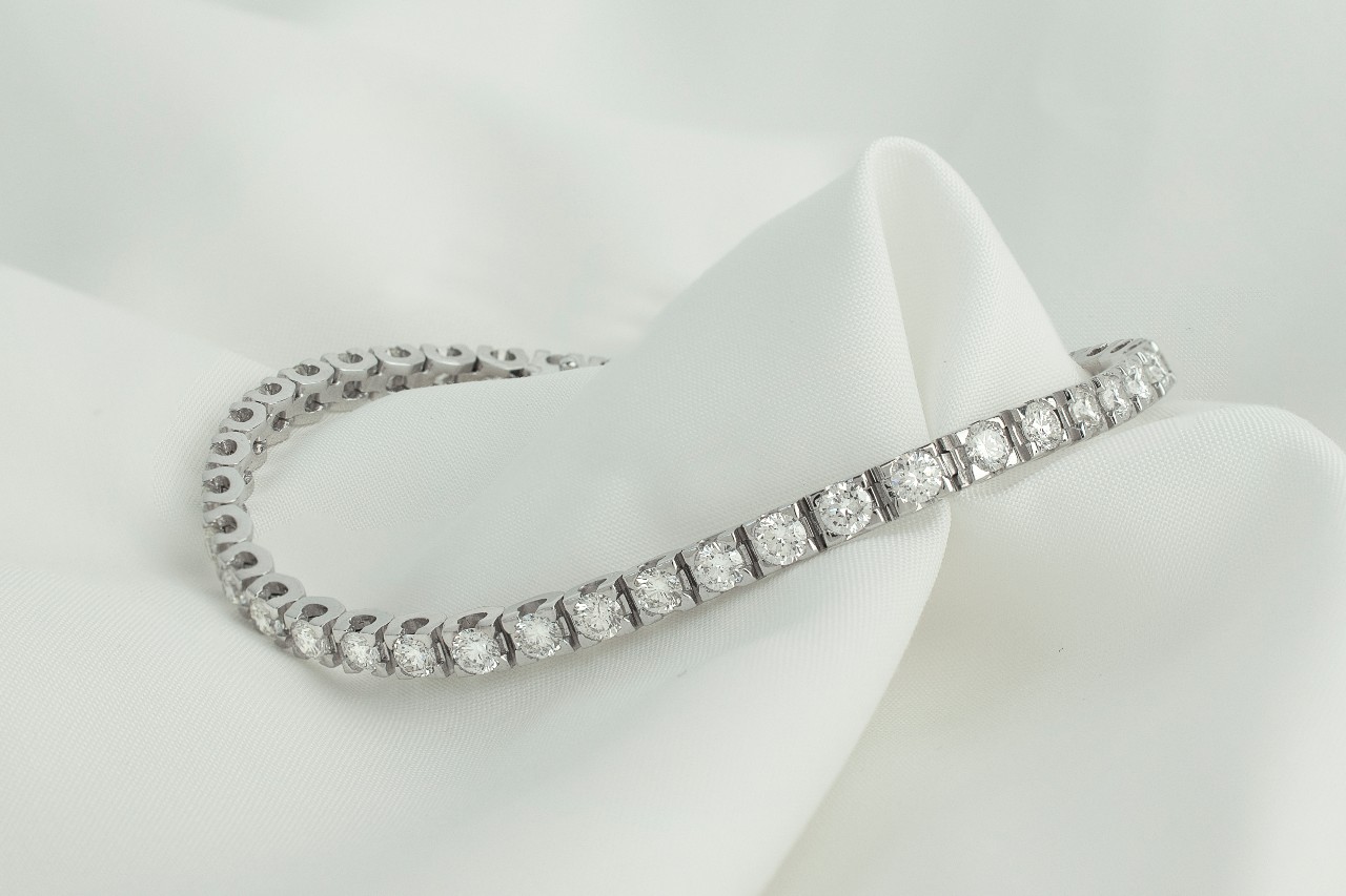 a diamond tennis bracelet lying on a piece of white fabric