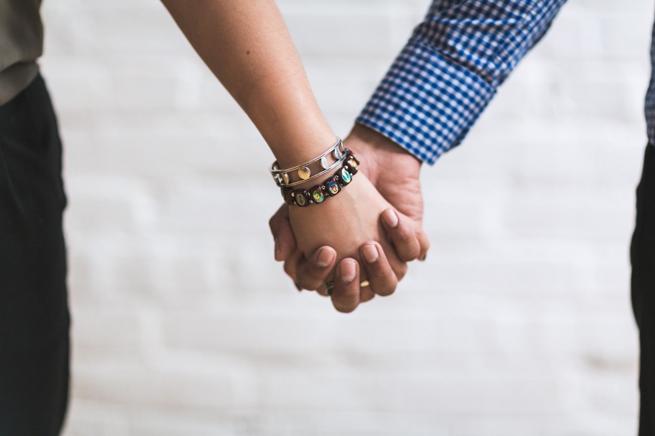 a woman wearing two bangles holds hands with her partner.