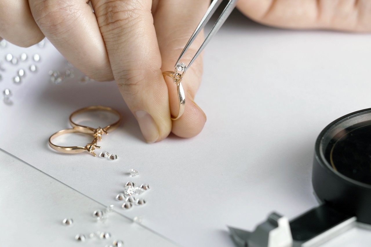 A jeweler sets diamonds into three solitaire engagement rings.
