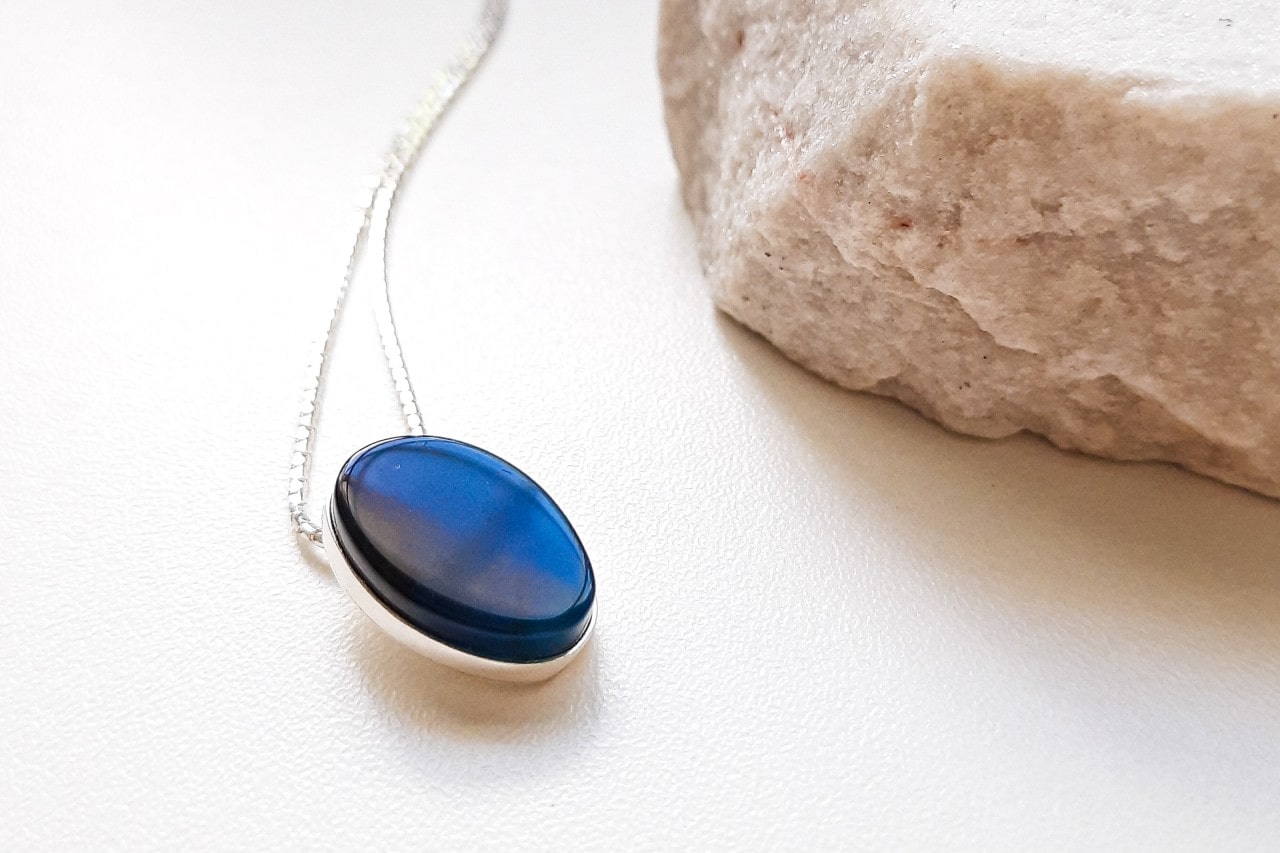 a white gold pendant necklace featuring a dark blue gemstone next to a white rock
