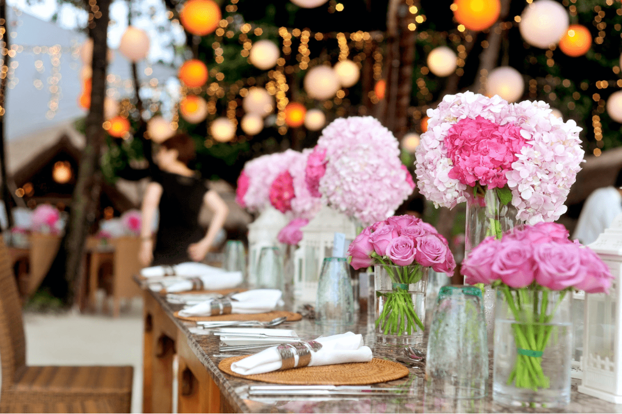 an elaborate table set for a wedding reception with a variety of pink floral centerpieces