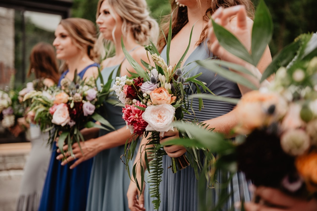 a row of bridesmaids wearing blue dresses and holding their bouquets