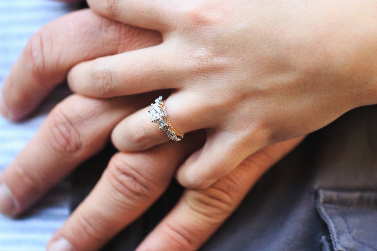 close up image of a couple holding hands, the woman wearing a mixed metal engagement ring