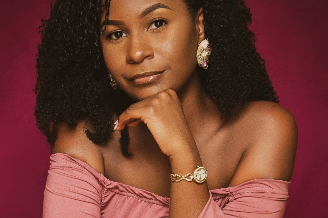 a woman posing with her hand under her chin wearing a jewelry-inspired watch