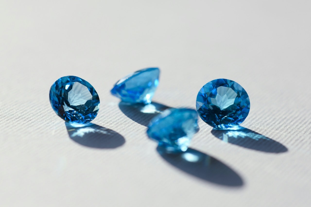 four round cut aquamarine stones sitting on a white surface