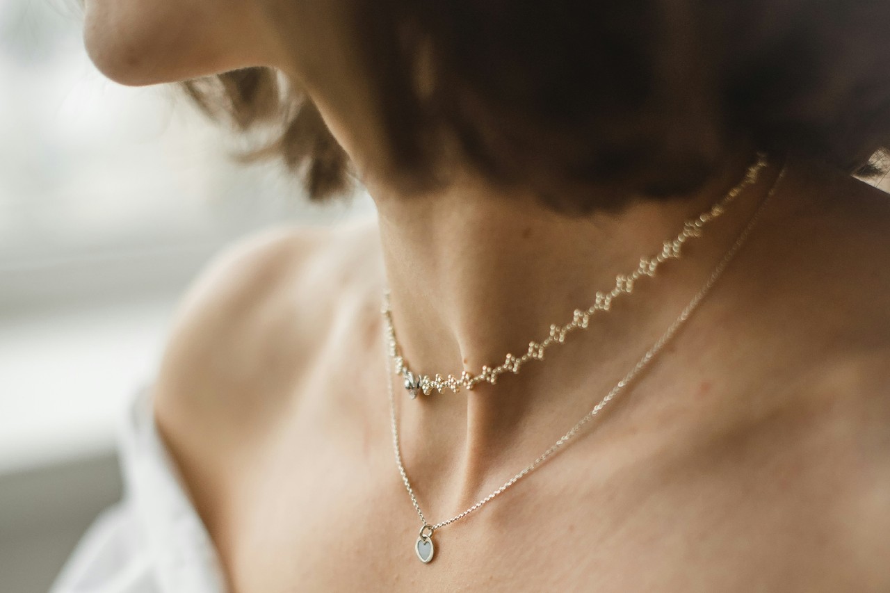 close up image of a womans neck adorned with two fine chain necklaces