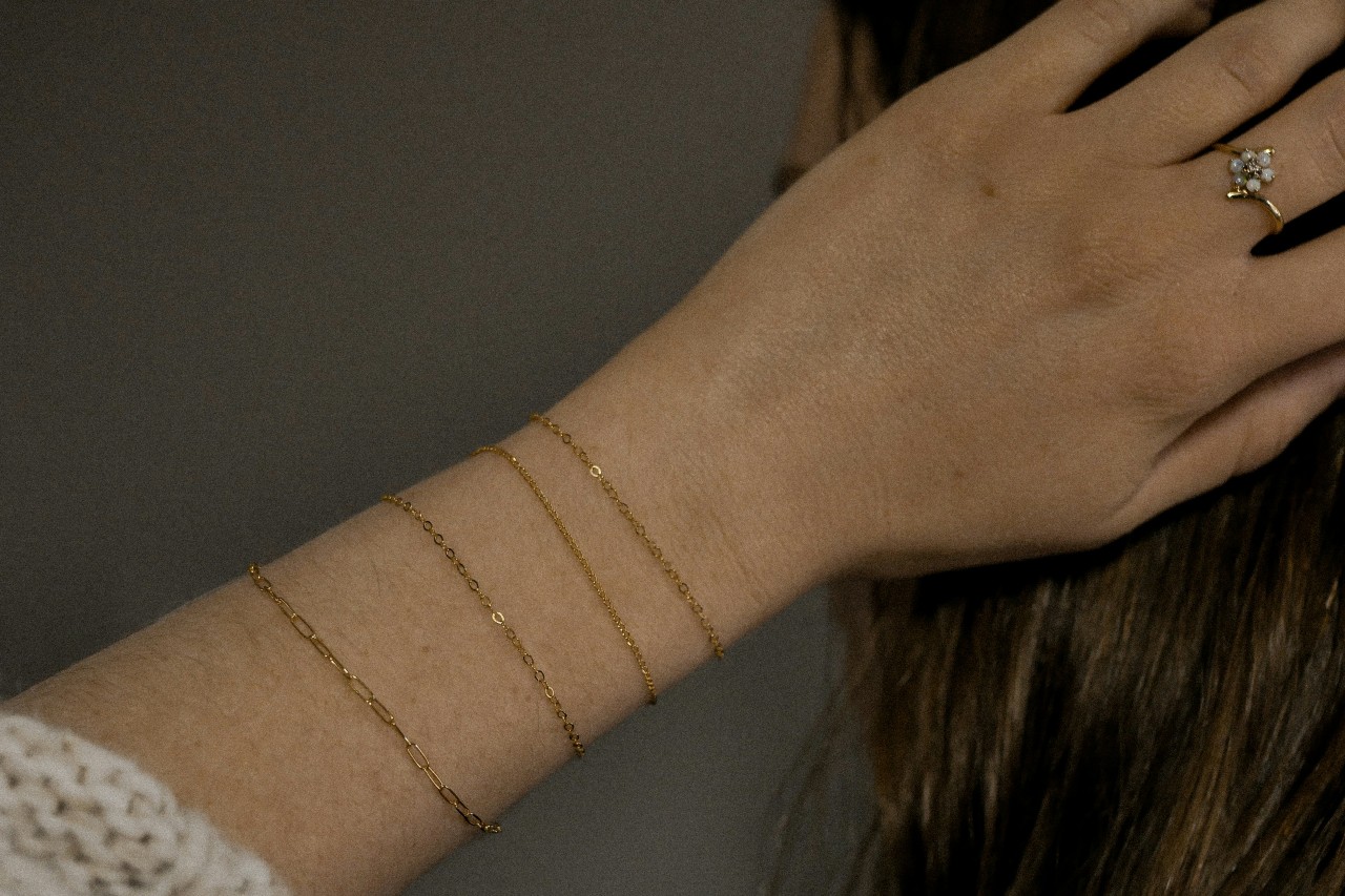 close up image of a woman’s wrist adorned with four permanent bracelets with different link types
