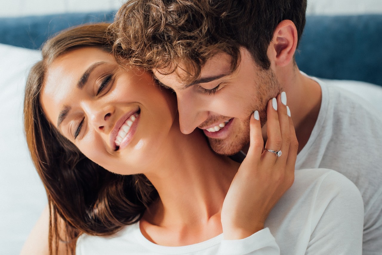 a woman embracing a man while wearing an engagement ring