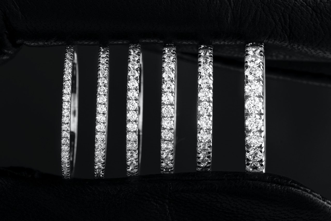 six white gold and diamond wedding bands ascending in diamond size on a black background