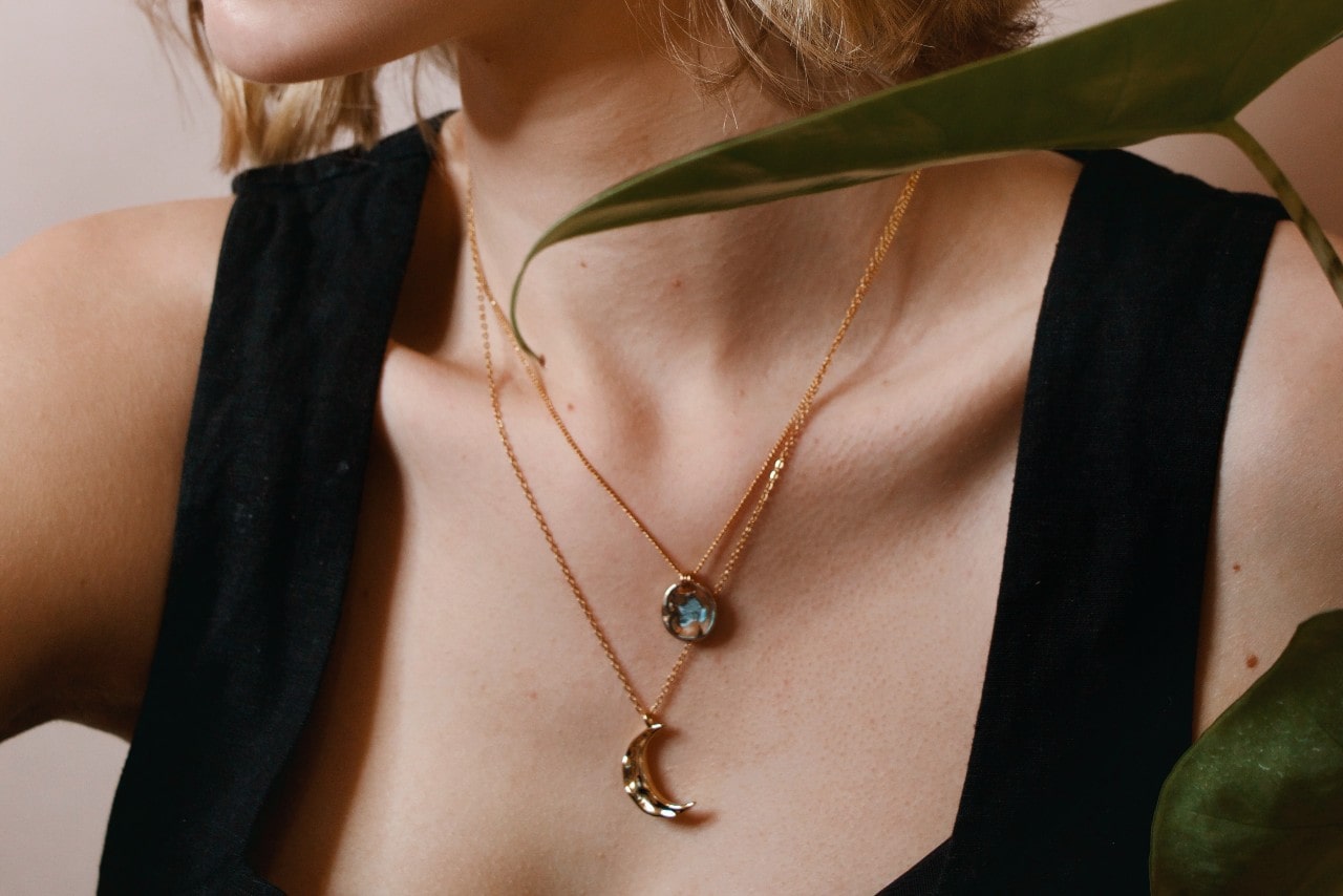 close up of a woman’s neckline wearing two rose gold pendant necklaces