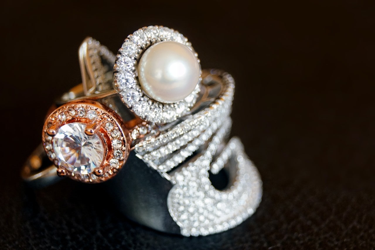 a stack of three large fashion rings against a black background