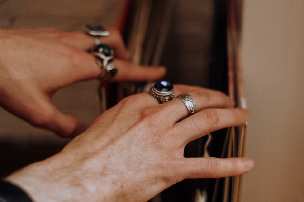 a person wearing silver rings and looking through records